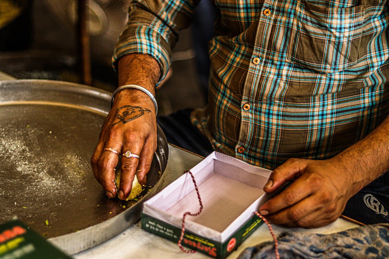 services-04 Street vendor shaping and boxing traditional Indian sweets with focus on hands and details.