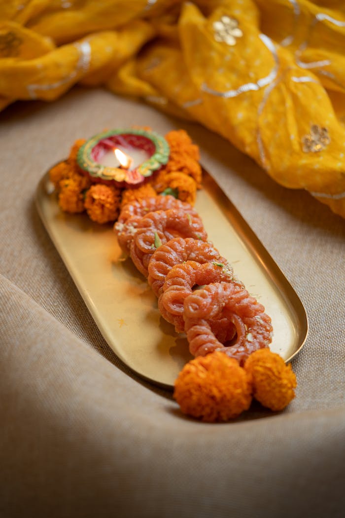 services-02 Intricate Indian sweets with vibrant marigold flowers and diya on a golden tray, perfect for festive occasions.