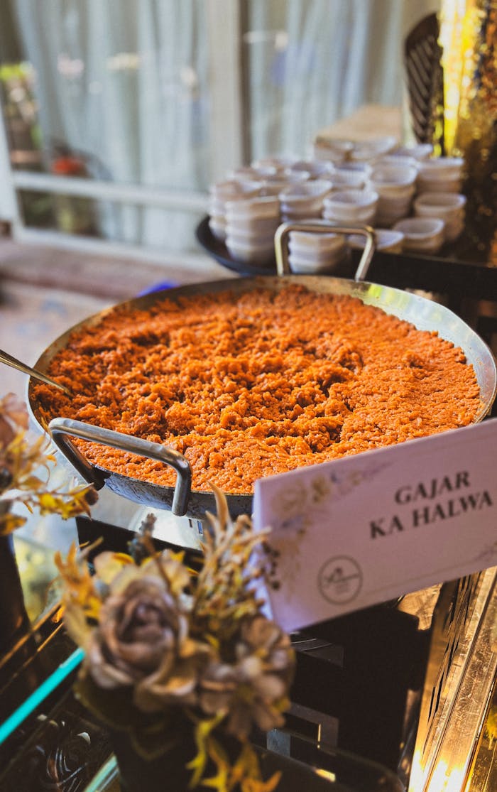 services-03 Close-up of a large serving of Gajar Ka Halwa at an indoor buffet table.